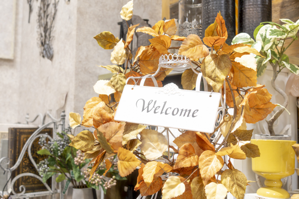 オレンジ色の葉に囲まれたWelcomeプレート付きの秋のリース